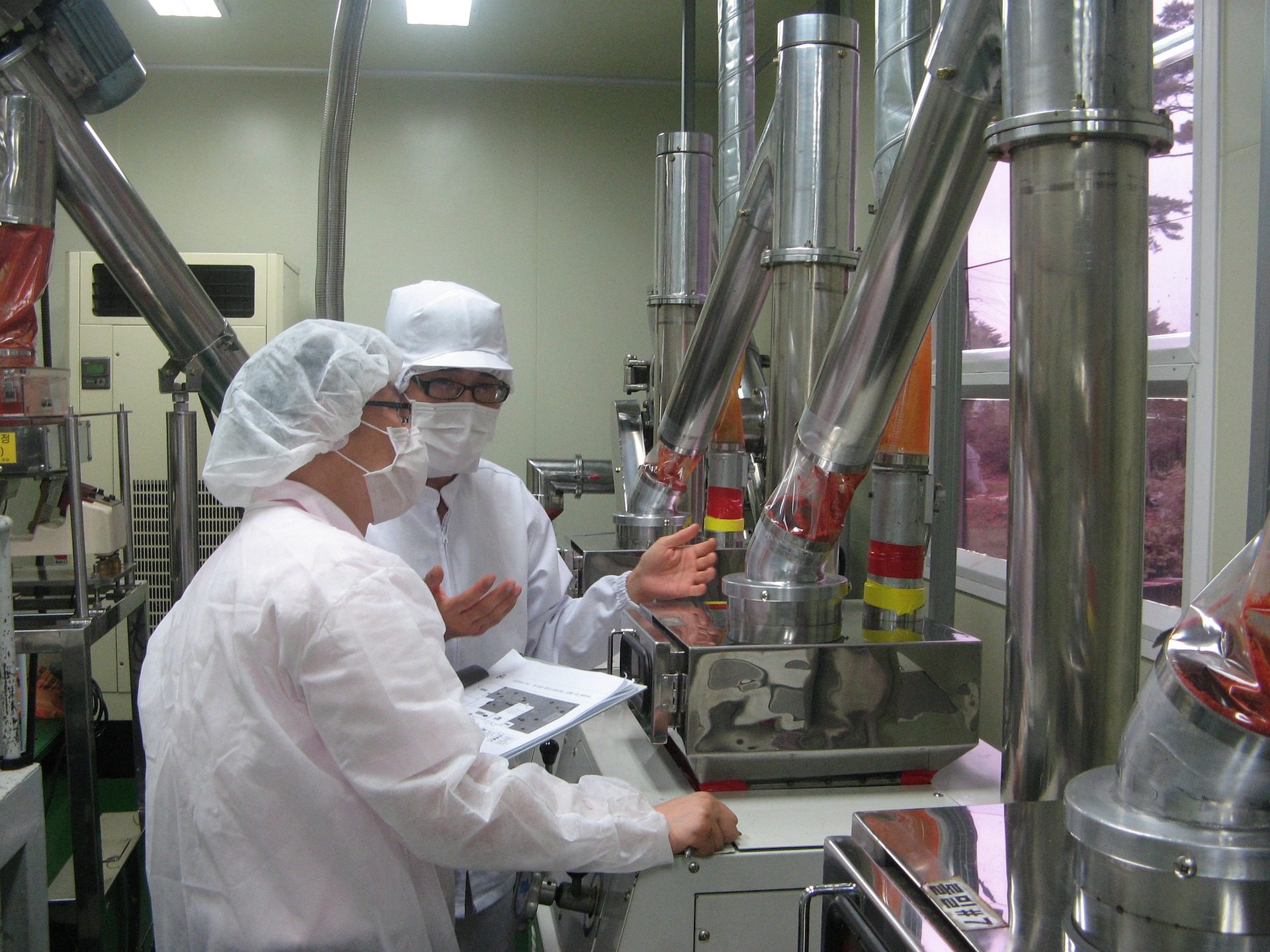 A couple of scientists inspecting a machine wearing mask